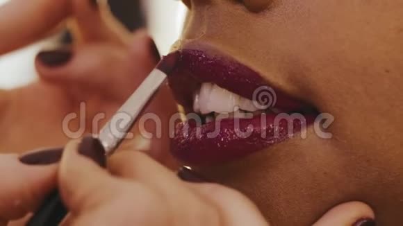 在时尚工作室将口红精确涂在女性嘴唇上视频的预览图