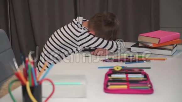 一个白人男孩睡在练习本上的肖像小学生在家做作业后很累可爱的孩子视频的预览图