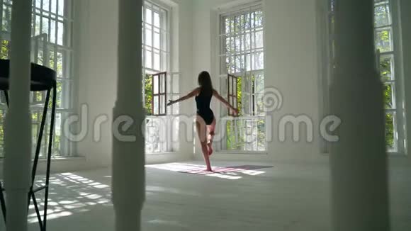 可爱的年轻女子正在家里锻炼健康的白种人女孩站在白色大房间的垫子上视频的预览图