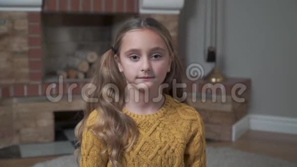 一个穿着芥末毛衣的白人女孩看着相机微笑的肖像可爱的小孩坐在前面视频的预览图