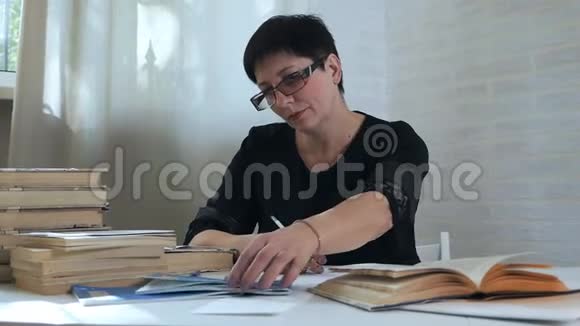 一个戴眼镜的女人手里拿着铅笔在纸上做笔记思考和思考写诗和诗歌创造力视频的预览图