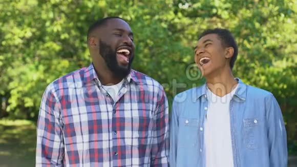 积极的儿子和父亲在户外笑开玩笑一起玩亲戚们视频的预览图