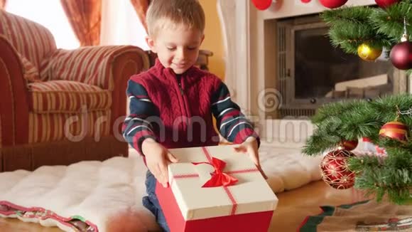 4k视频快乐微笑的小男孩从圣诞礼品盒盖上取下玩具火车视频的预览图