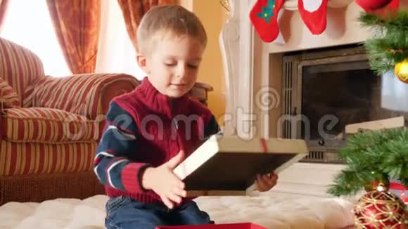 4k视频快乐微笑的小男孩拿着圣诞礼物或圣诞礼物摇着礼物盒视频的预览图
