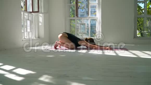 可爱的年轻红发健康的白种人女人在白色的大房间里的垫子上练习瑜伽年轻女子视频的预览图