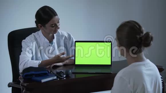 专业女医生告诉女性病人一些事情并用手显示在绿色屏幕上的笔记本电脑概念视频的预览图