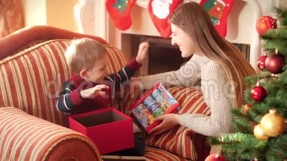 年轻母亲在给小儿子圣诞礼物后亲吻他的4K镜头家庭捐赠和接收视频的预览图