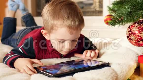 特写4k视频微笑的小男孩在数码平板电脑上玩游戏同时躺在家里的塔姆树下视频的预览图