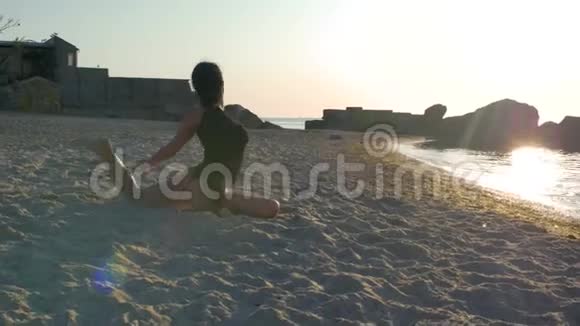 穿着黑色紧身衣的健身女性大腿上的纹身在海边的沙滩上或阳光下的海洋上做瑜伽4k4k视频视频的预览图