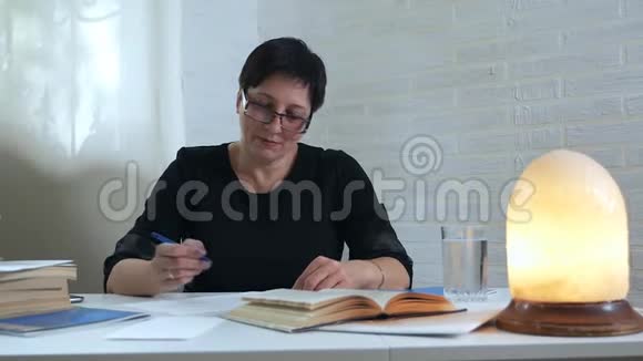 一位穿着黑色衣服和眼镜的女诗人坐在桌边写了一首诗扔了一块泡腾的药片和维生素视频的预览图