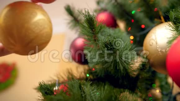 特写4k视频的女性手把金色华丽的宝布尔放在圣诞树树枝上冬天的完美镜头视频的预览图