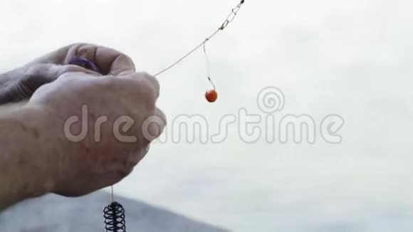特写镜头一个老渔夫的手在钓鱼钩上踩着鱼饵视频的预览图