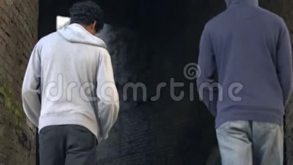 两个穿着连帽衫的非洲青少年一起在危险的城市地区散步视频的预览图