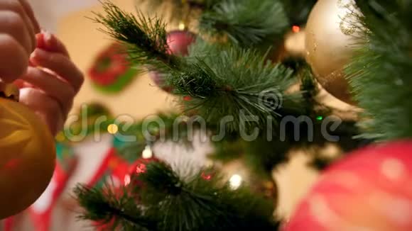 特写4k视频的年轻女子悬挂和旋转金色闪闪发光的华丽宝珠在圣诞树准备工作的人视频的预览图