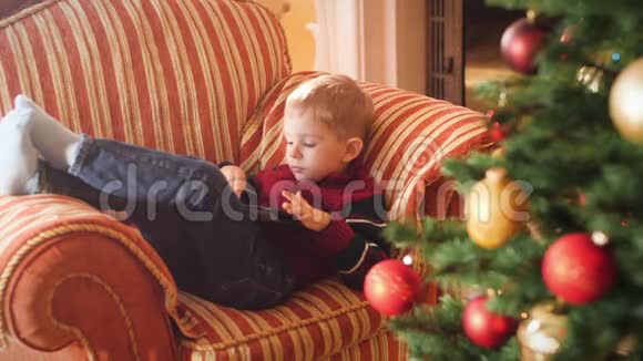 小男孩躺在客厅沙发上用平板电脑的4k视频儿童在寒假和视频的预览图