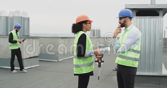 非常有魅力的女人和漂亮的工程师在建筑工地的屋顶上交谈视频的预览图