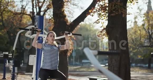 十几岁的女孩在一个模拟器上在公园里练习健身视频的预览图
