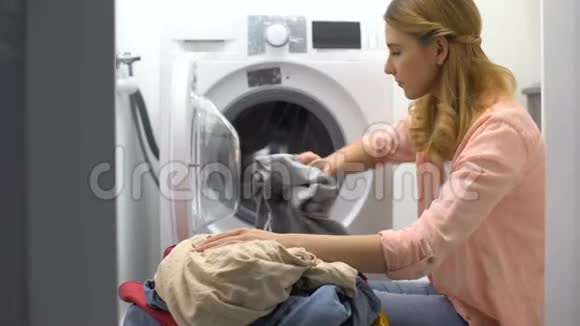 疲惫的女人在洗衣机里装衣服烦透了家务视频的预览图