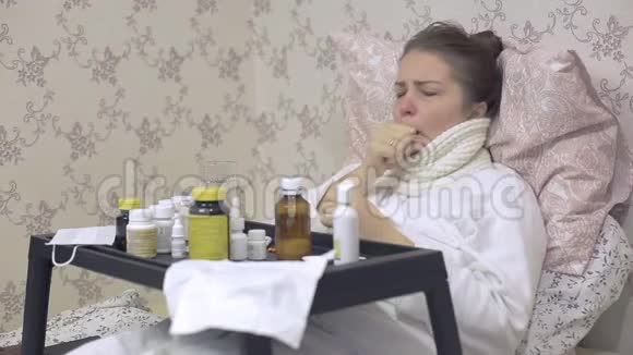 一个感冒的女人躺在床上桌子上放着很多药物疾病期间咳嗽很厉害视频的预览图