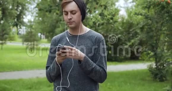 希普斯特在夏季公园听智能手机音乐视频的预览图