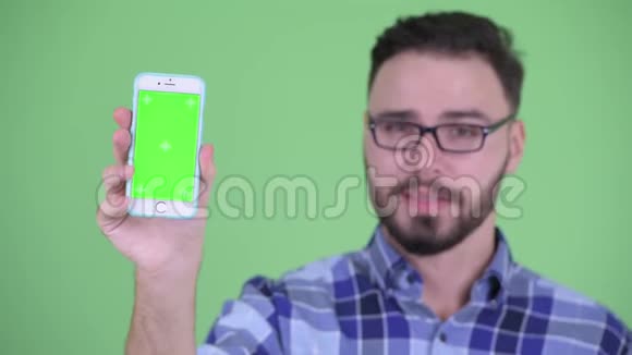 一个年轻的留着胡子的年轻时髦男人脸上露出手机竖起大拇指视频的预览图