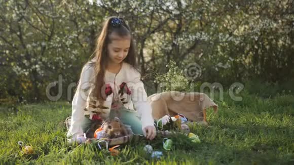 院子里的女孩坐在草地上树上开花复活节用彩蛋装饰视频的预览图