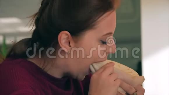 快餐厅里吃纯素汉堡的年轻美女画像年轻女子在城里的咖啡厅吃纯素沙玛视频的预览图