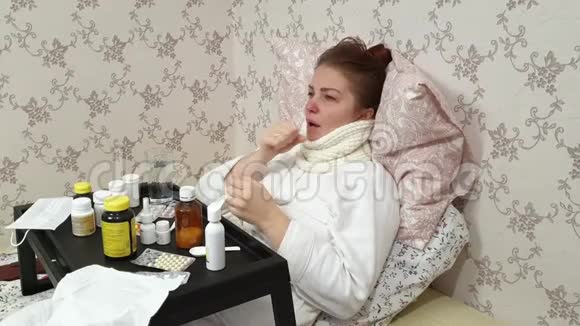 一个感冒的女人躺在床上桌子上放着很多药物疾病期间咳嗽很厉害视频的预览图