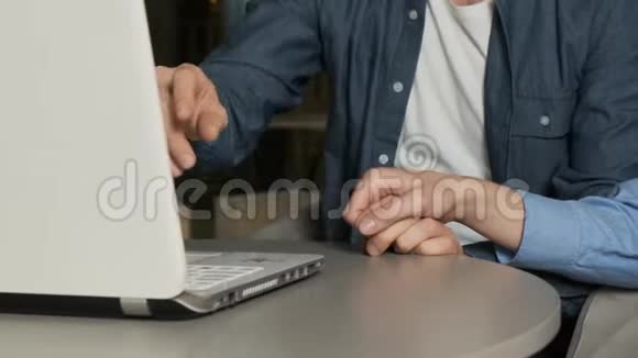 年轻夫妇在笔记本电脑上工作一个男人用手指指着坐在办公室里办公桌前的屏幕视频的预览图