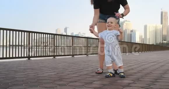 微笑的男孩牵着母亲手迈出了夏天散步长廊的第一步视频的预览图