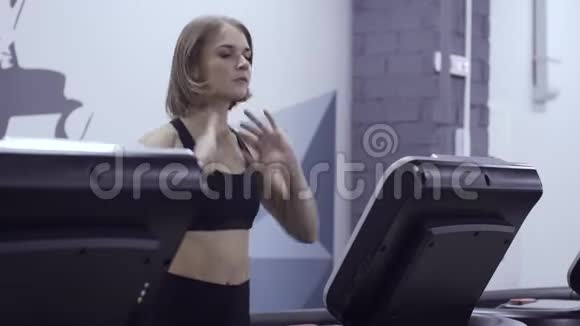 年轻运动的女人在健身房的跑步机上走得很快视频的预览图