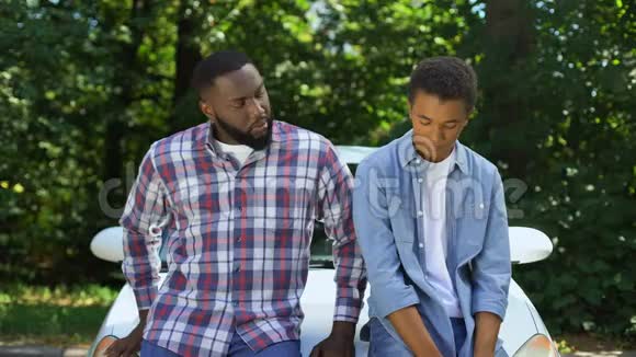 非裔美国父亲要求汽车钥匙青少年儿子汽车背景家长控制视频的预览图