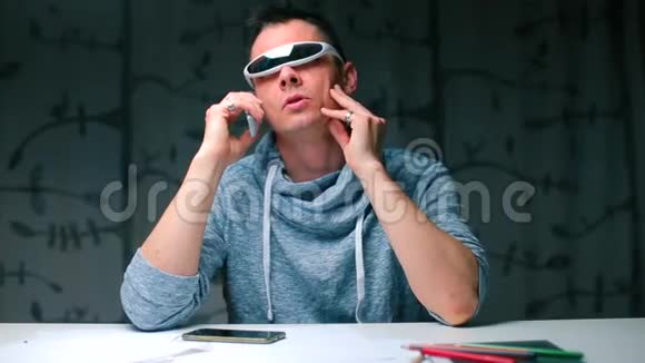 一个戴着现代眼镜的人正坐在桌子旁打电话视频的预览图