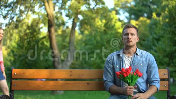女孩闭上男友的眼睛在公园等着她带着一束鲜花惊喜视频的预览图
