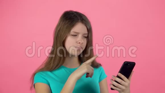 小女孩在电视上聊天在粉红色的背景下在演播室的手机上聊天慢动作视频的预览图