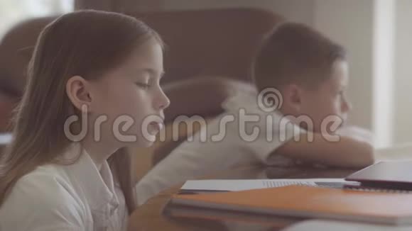 姐姐和哥哥坐在桌子上从学校做作业女孩在桌子上睡着了男孩还在读书视频的预览图