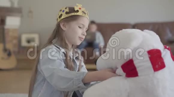 肖像美丽的女孩坐在地板上抱着一只巨大的白色的熊视频的预览图