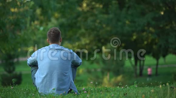 在公园里坐在草地上的人的后景在孤独中享受周末视频的预览图
