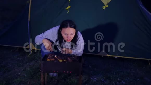 一个女人在帐篷里一堆火烤着肉燃烧着煤视频的预览图