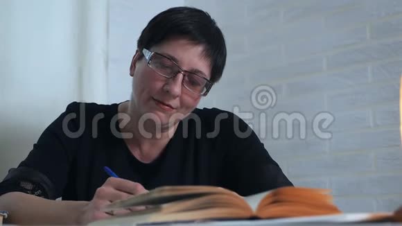 一个戴眼镜的女人手里拿着铅笔在纸上做笔记思考和思考写诗疲劳女人视频的预览图