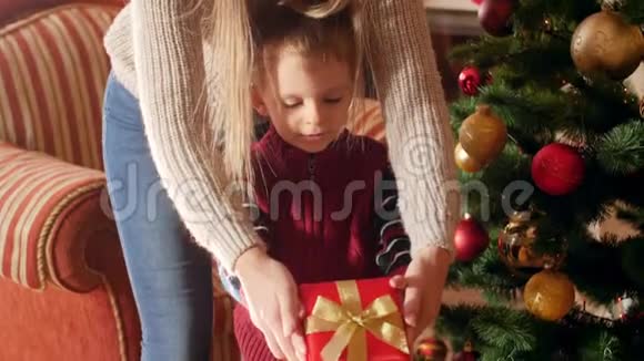 小母亲把圣诞礼物装在盒子里给站在圣诞树旁边的小儿子的视频儿童视频的预览图