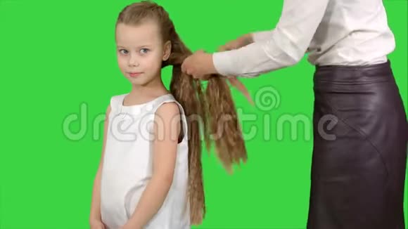 母亲在绿色屏幕上给女儿做发型Chroma键视频的预览图