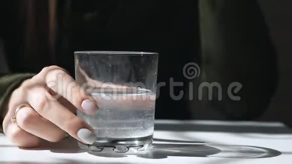 杯子里疼痛的泡腾片溶解了阿斯匹林药片在玻璃杯里休伦一个女孩的手在计划视频的预览图