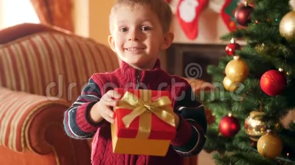 快乐微笑的小男孩在盒子里拿着圣诞礼物的视频并在镜头中展示他的礼物接收儿童视频的预览图