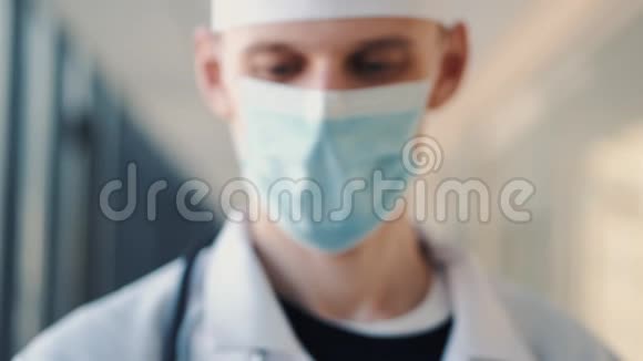 戴着医用帽子和口罩的男医生正在展示一些注射器视频的预览图