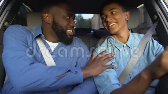 微笑美国父亲赞扬儿子学习驾驶汽车父母帮助家庭视频的预览图