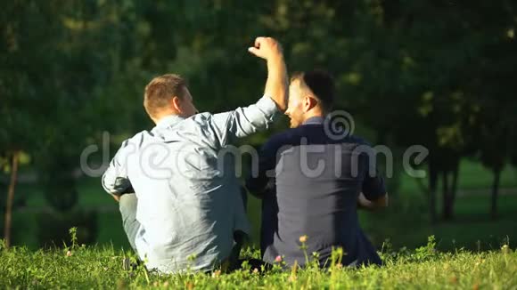 男人拥抱朋友在阳光公园享受休闲时光后景相聚视频的预览图