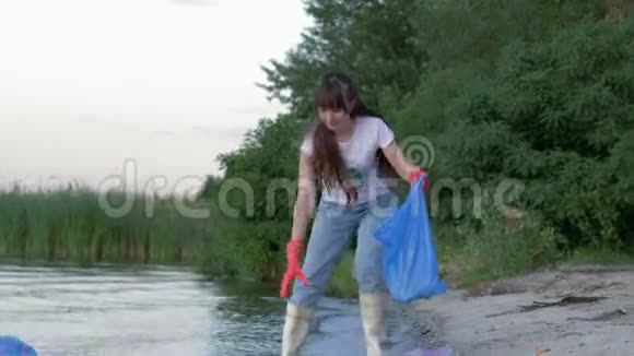 塑料污染问题年轻的志愿者妇女穿上橡胶靴从垃圾中清理海滩收集聚乙烯视频的预览图