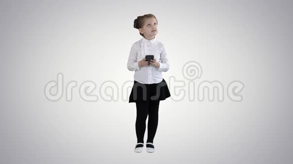 可爱的小女孩在智能手机上看并在梯度背景下写一条信息视频的预览图