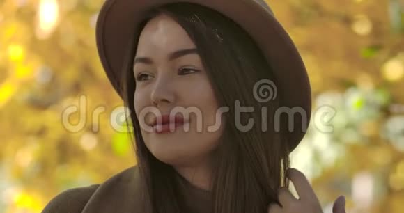 站在黄叶背景上的棕色帽子的迷人的欧洲女孩的特写肖像自信视频的预览图